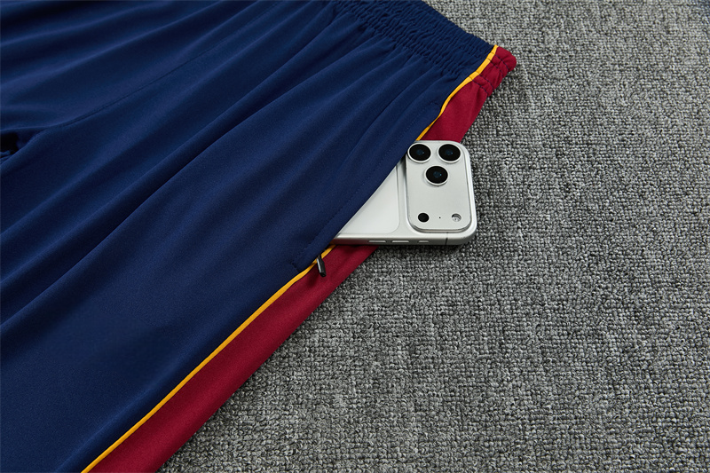 Detalle del bolsillo lateral con cremallera del pantalón azul del chándal Barcelona 26-27 con panel granate y ribete amarillo