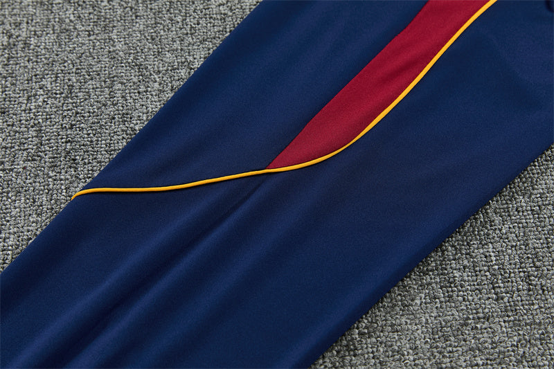 Detalle lateral del pantalón azul del chándal Barcelona 26-27 con inserto granate y ribete amarillo