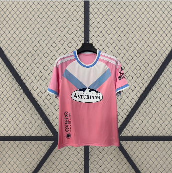 Vista frontal de la camiseta Real Oviedo 26-27 visitante en rosa, con gráfico angular blanco y azul, cuello redondo y manga corta