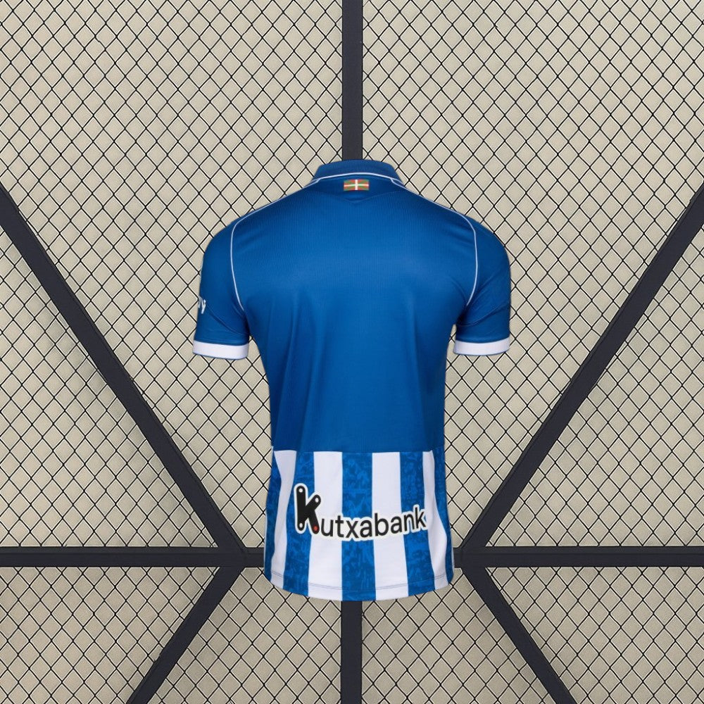 Vista trasera de la camiseta Alavés 26-27 local en color azul, con panel inferior de rayas verticales azules y blancas