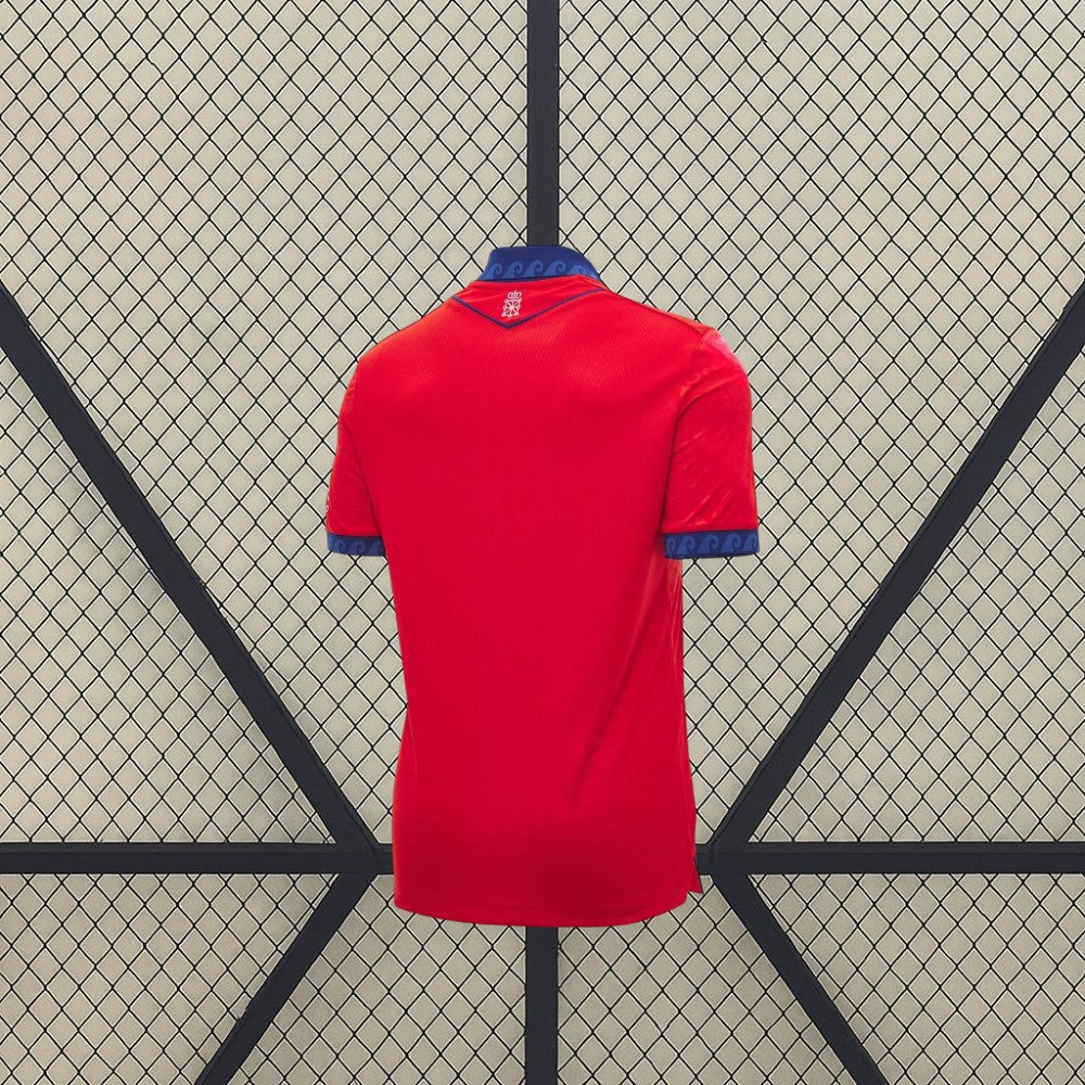 Vista trasera de la camiseta Osasuna 26-27 local en color rojo, con cuello y puños azules y pequeño detalle gráfico bajo el cuello