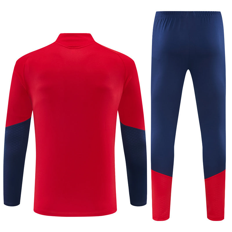 Vista trasera del Chándal España 26-27 media cremallera con chaqueta roja y pantalón azul marino con bajos rojos
