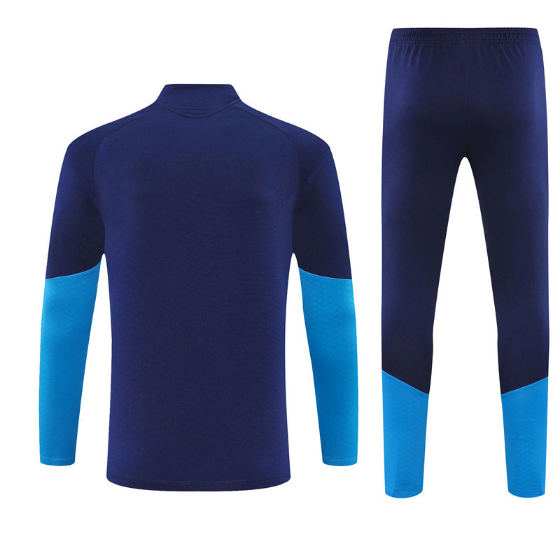 Vista trasera del chándal España 26-27 Modelo 2 con chaqueta y pantalón azul marino y paneles inferiores azul celeste