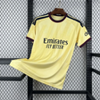 Camiseta Arsenal 26-27 tercera equipación vista frontal en amarillo con patrón tonal, cuello granate y azul marino y detalles oscuros en hombros