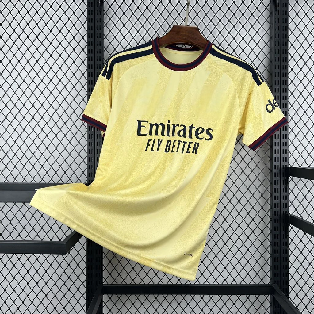 Camiseta Arsenal 26-27 tercera equipación vista frontal en amarillo con patrón tonal, cuello granate y azul marino y detalles oscuros en hombros