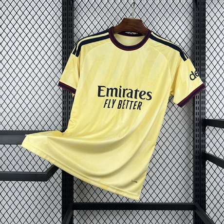 Camiseta Arsenal 26-27 tercera equipación vista frontal en amarillo con patrón tonal, cuello granate y azul marino y detalles oscuros en hombros