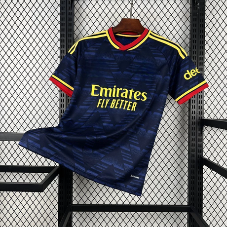Camiseta Arsenal 26-27 visitante vista frontal en azul marino con patrón geométrico tonal, cuello rojo y amarillo y detalles amarillos en hombros