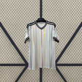 Camiseta Japón 26-27 visitante Mundial 2026 vista frontal en blanco con líneas verticales multicolor, cuello en V negro y puños oscuros