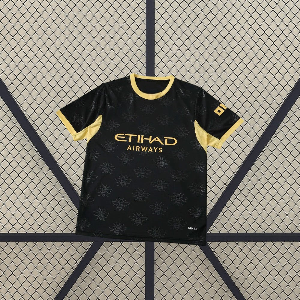 Camiseta Manchester City 26-27 visitante vista frontal en negro con patrón tonal de abejas, cuello y mangas dorados y detalle DRYCELL
