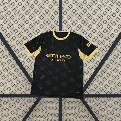Camiseta Manchester City 26-27 visitante vista frontal en negro con patrón tonal de abejas, cuello y mangas dorados y detalle DRYCELL