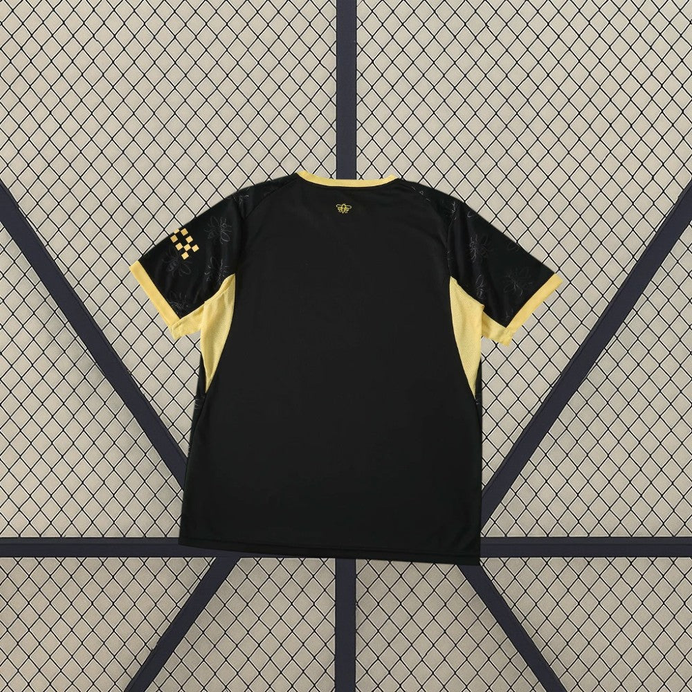 Camiseta Manchester City 26-27 visitante vista trasera en negro con paneles laterales dorados, patrón de abejas en mangas y detalle en la nuca