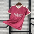 Camiseta R.M. 26-27 tercera equipación vista frontal en rosa oscuro con patrón geométrico tonal, cuello en V crema y detalles en los hombros