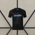 Camiseta Tenerife 26-27 visitante vista frontal en negro con detalles azul turquesa, cuello en V y patrón tonal