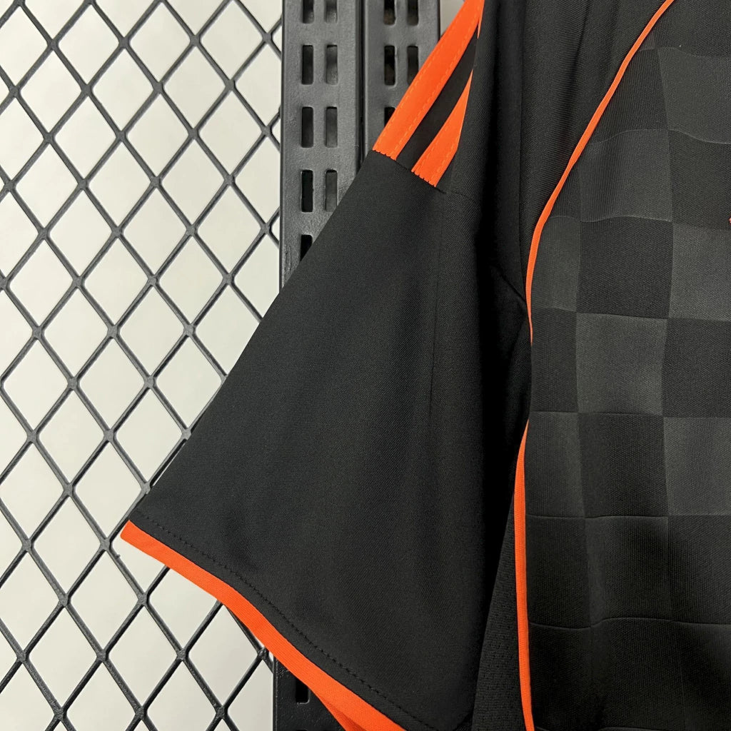 Detalle de la manga negra con ribete naranja y costura lateral de la camiseta Como 25-26 tercera equipación