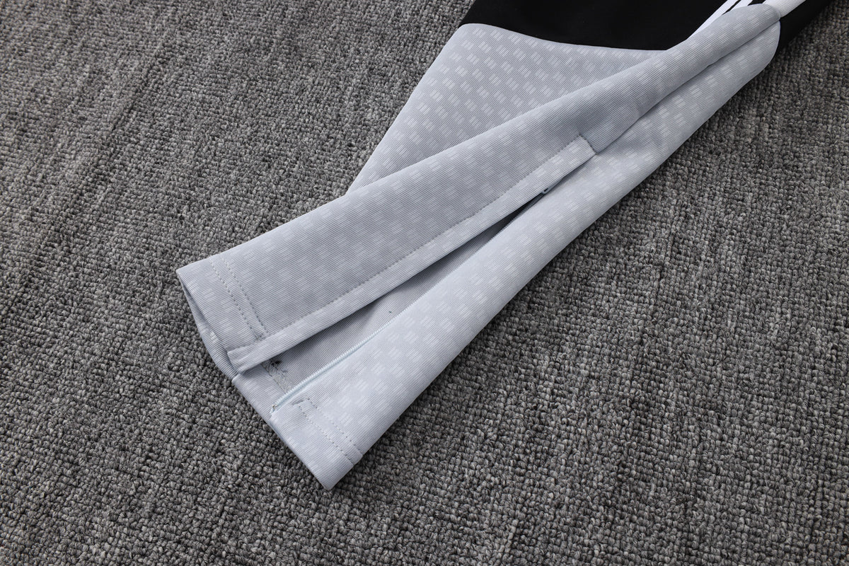 Detalle del bajo del pantalón del chándal R.M. 26-27 modelo 3 con panel gris claro y apertura con cremallera