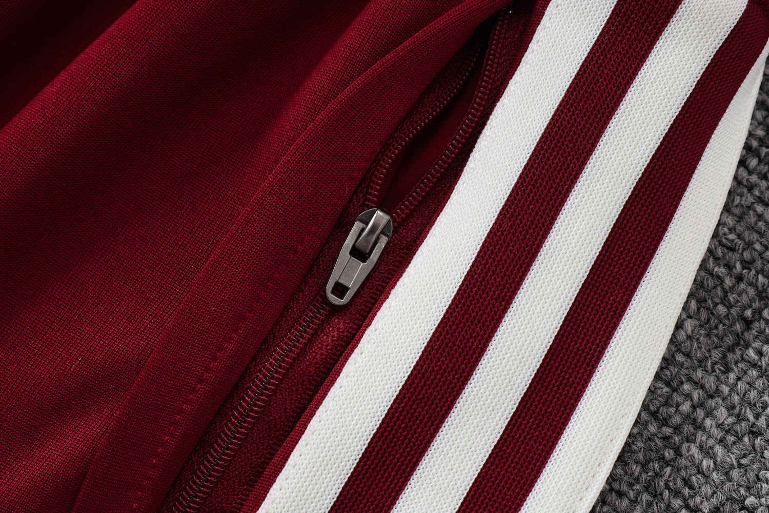 Detalle del bolsillo con cremallera y franjas blancas laterales del pantalón granate del chándal España 26-27 Modelo 1
