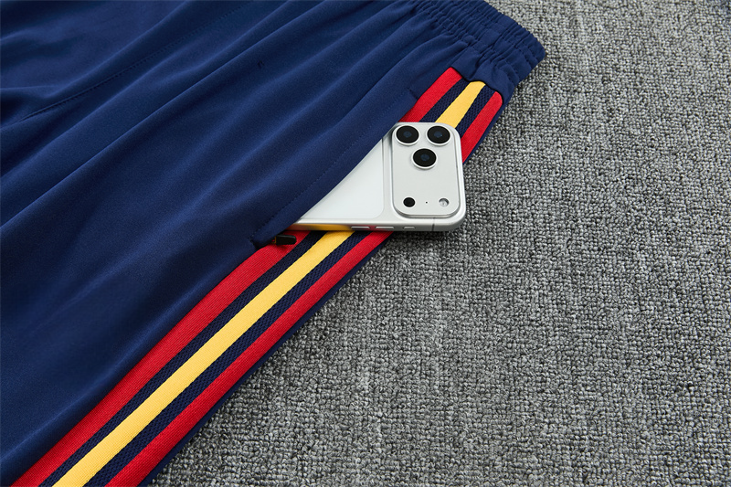 Detalle del bolsillo del pantalón azul marino del Chándal España 26-27 con franjas rojas y amarillas