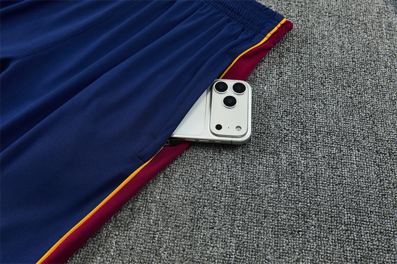 Detalle del bolsillo lateral con cremallera del pantalón azul del chándal Barcelona 26-27 con panel granate y ribete amarillo