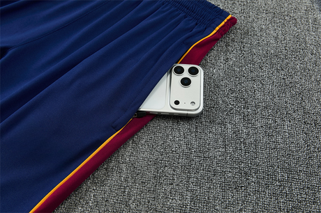 Detalle del bolsillo lateral con cremallera del pantalón azul del chándal Barcelona 26-27 con panel granate y ribete amarillo