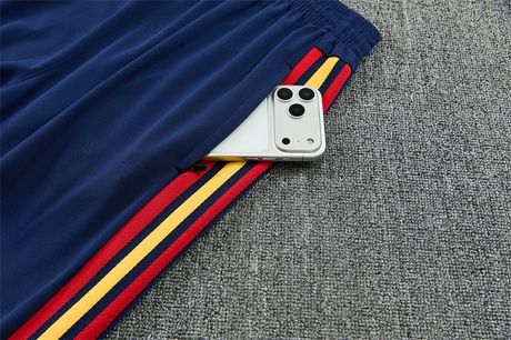 Detalle del bolsillo lateral del pantalón azul marino del Chándal España 26-27 con franjas rojas y amarillas
