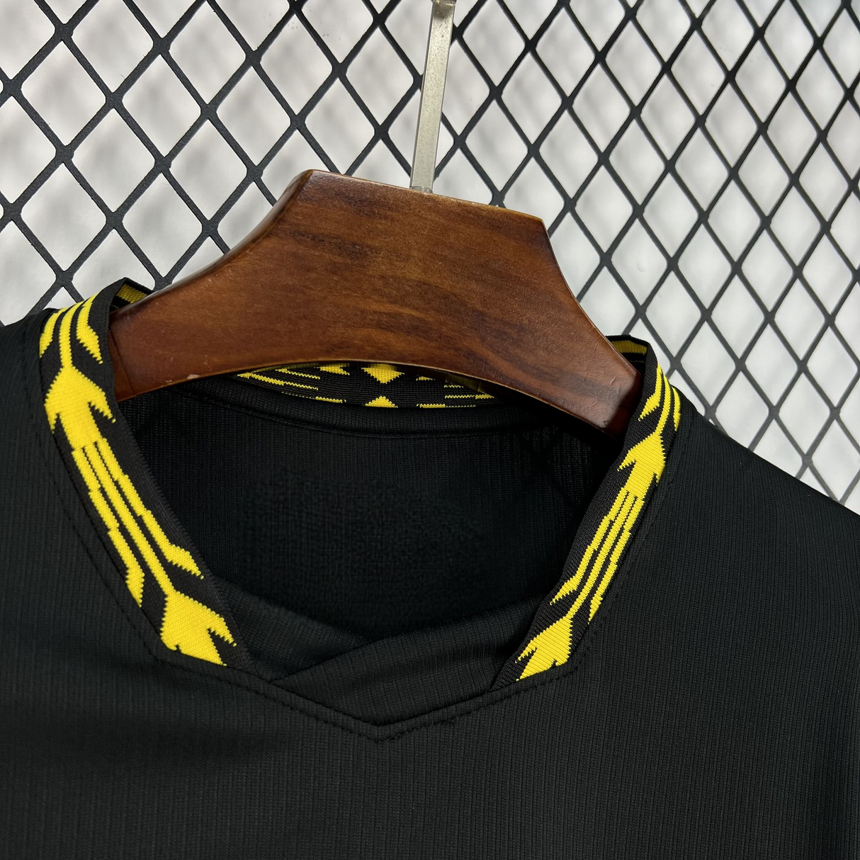 Detalle del cuello en pico de la camiseta Chelsea 26-27 visitante, con acabado amarillo estampado y tejido negro texturizado