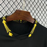 Detalle del cuello en pico de la camiseta Chelsea 26-27 visitante, con acabado amarillo estampado y tejido negro texturizado