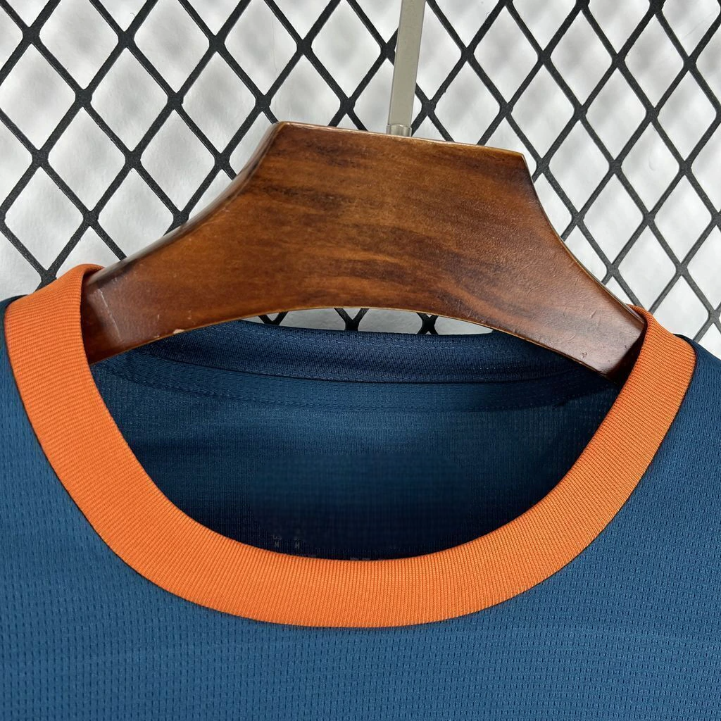 Detalle del cuello redondo naranja de la camiseta Valencia 26-27 visitante y del tejido azul oscuro microperforado