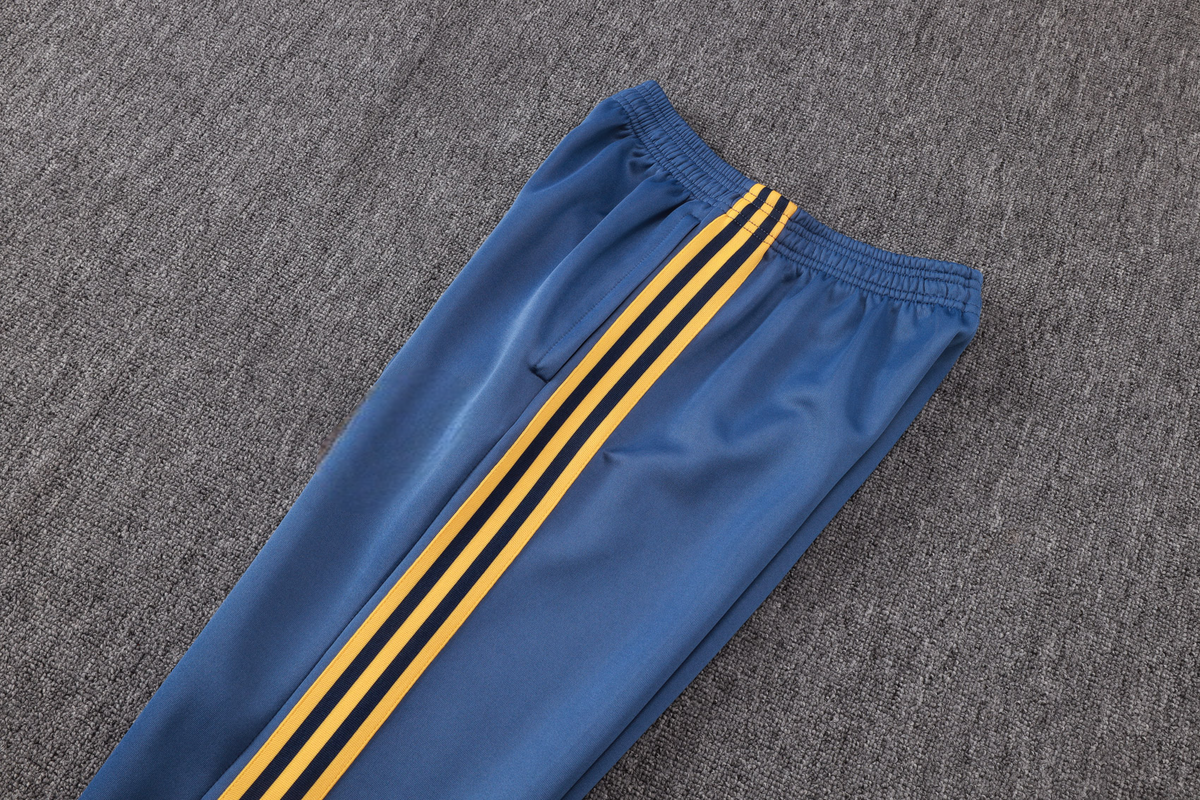 Detalle del pantalón azul del chándal Arsenal 26-27 Modelo 2 con cintura elástica, bolsillo lateral y franjas amarillas
