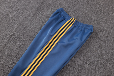 Detalle del pantalón azul del chándal Arsenal 26-27 Modelo 2 con cintura elástica, bolsillo lateral y franjas amarillas