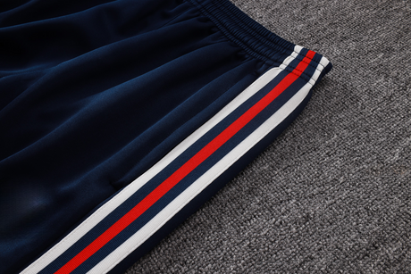 Detalle del pantalón azul marino del chándal Bayern Munich 26-27 Modelo 1 con cintura elástica y franjas laterales rojas y blancas