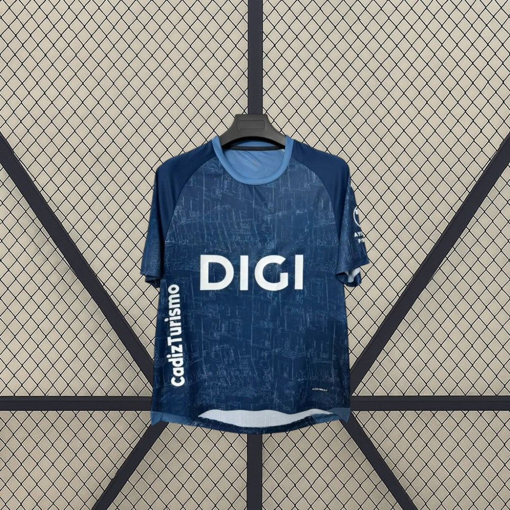 Detalle frontal de la camiseta Cádiz 26-27 visitante con patrón tonal azul, cuello redondo celeste y paneles oscuros en los hombros