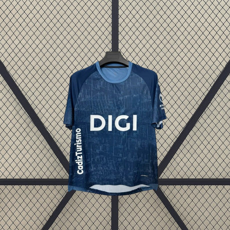 Detalle frontal de la camiseta Cádiz 26-27 visitante con patrón tonal azul, cuello redondo celeste y paneles oscuros en los hombros