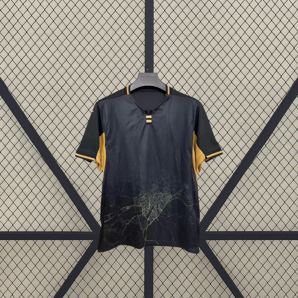 Detalle frontal de la camiseta Córdoba 26-27 Visitante negra y dorada con gráfico cartográfico inferior y cuello con abertura central
