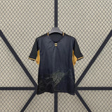Detalle frontal de la camiseta Córdoba 26-27 Visitante negra y dorada con gráfico cartográfico inferior y cuello con abertura central
