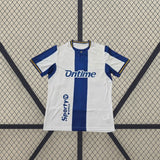 Detalle frontal de la camiseta Leganés 26-27 local con franja central azul, cuello con detalle dorado y mangas blancas y azules