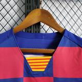Detalle frontal del cuello de pico de la camiseta Barcelona 19-20 retro con acabado azul y franjas interiores amarillas y rojas