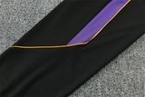 Detalle lateral del pantalón negro del chándal Barcelona 26-27 con inserto morado y ribete amarillo