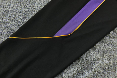 Detalle lateral del pantalón negro del chándal Barcelona 26-27 con inserto morado y ribete amarillo