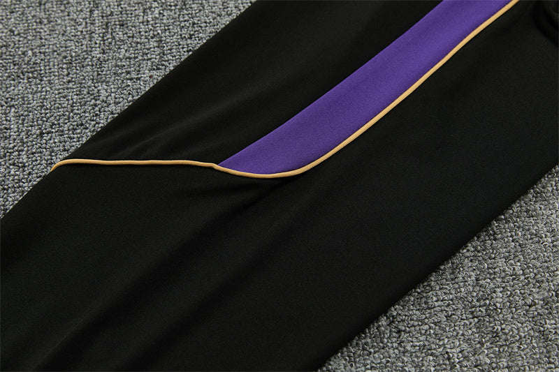 Detalle lateral del pantalón negro del chándal Barcelona 26-27 con panel morado y ribete dorado