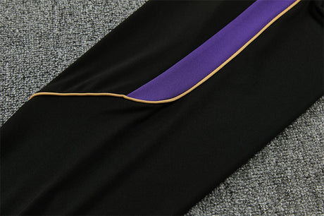 Detalle lateral del pantalón negro del chándal Barcelona 26-27 con panel morado y ribete dorado