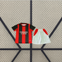 Equipación AC Milan 26-27 local para niño con camiseta de franjas rojas y negras y pantalón corto blanco con paneles rojos