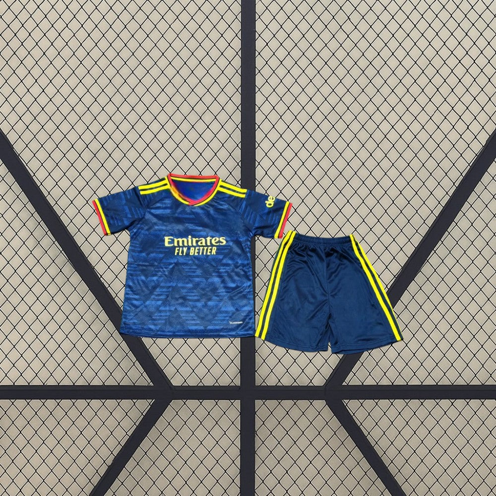 Equipación Arsenal 26-27 visitante niño vista frontal con camiseta azul marino de patrón tonal y pantalón azul con detalles amarillos