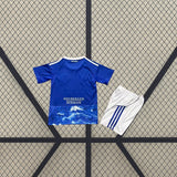 Equipación Como 25-26 local para niño vista trasera con camiseta azul y pantalón corto blanco con detalles azules