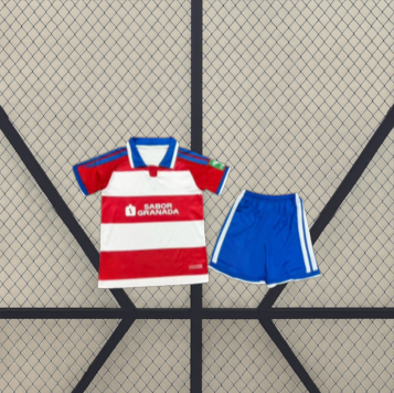 Equipación Granada 26-27 local para niño vista frontal con camiseta de franjas rojas y blancas y pantalón corto azul a juego
