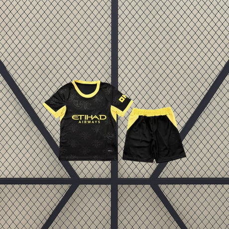 Equipación Manchester City 26-27 Visitante de niño con camiseta y pantalón negros, patrón de abejas y detalles amarillos