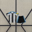 Equipación Newcastle 26-27 local para niño con camiseta de franjas blancas y negras y pantalón corto negro con detalles azul celeste