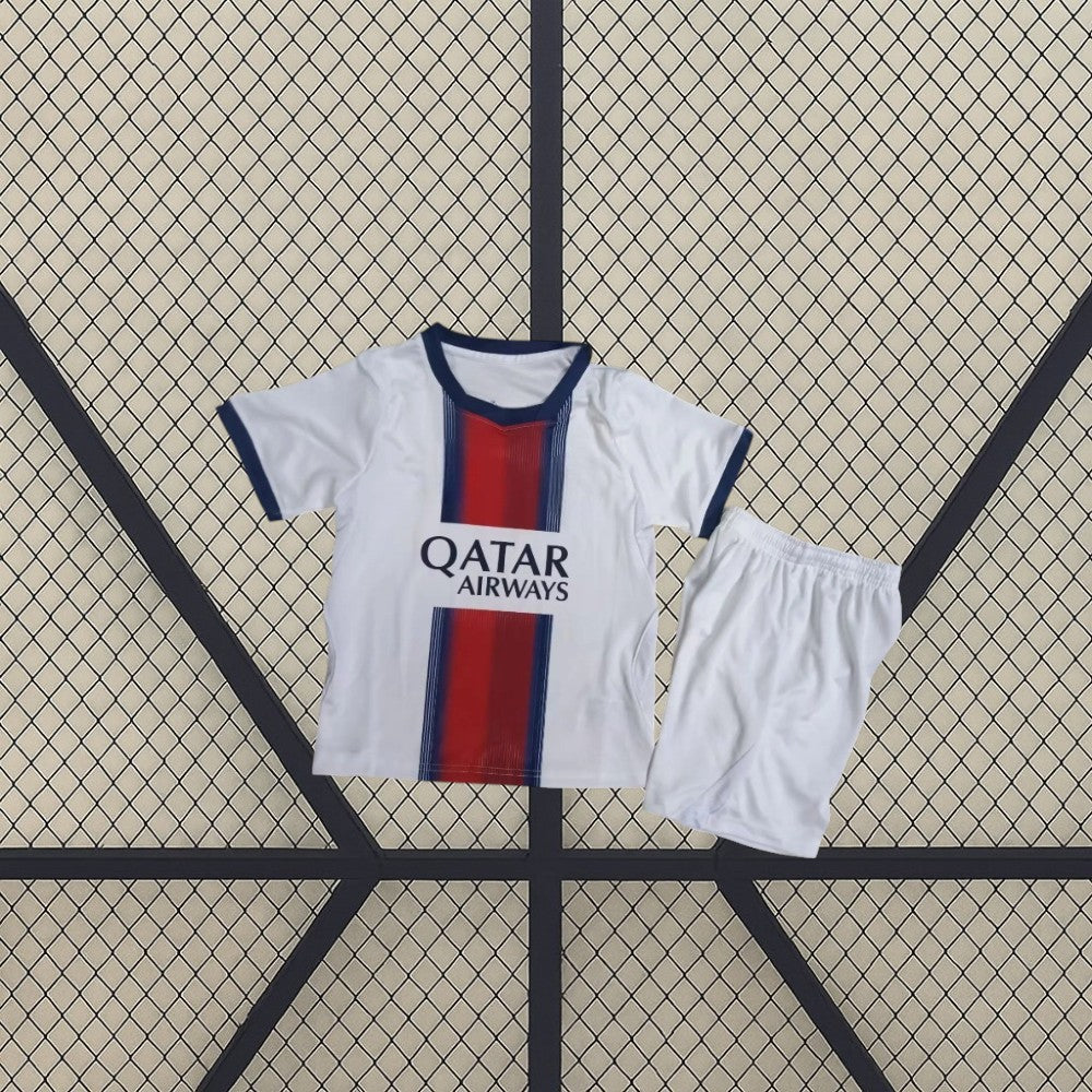 Equipación PSG 26-27 visitante niño vista frontal con camiseta blanca, franja central azul marino y roja y pantalón blanco