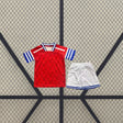 Equipación RCD Espanyol 26-27 visitante infantil con camiseta roja de patrón geométrico y pantalón corto blanco con detalles azules