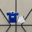 Equipación Real Oviedo 26-27 local infantil con camiseta azul de cuello polo blanco y pantalón corto blanco con franjas laterales azules