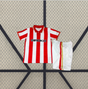 Equipación Sporting de Gijón 26-27 local niño vista frontal con camiseta de franjas rojas y blancas y pantalón corto blanco con detalles laterales